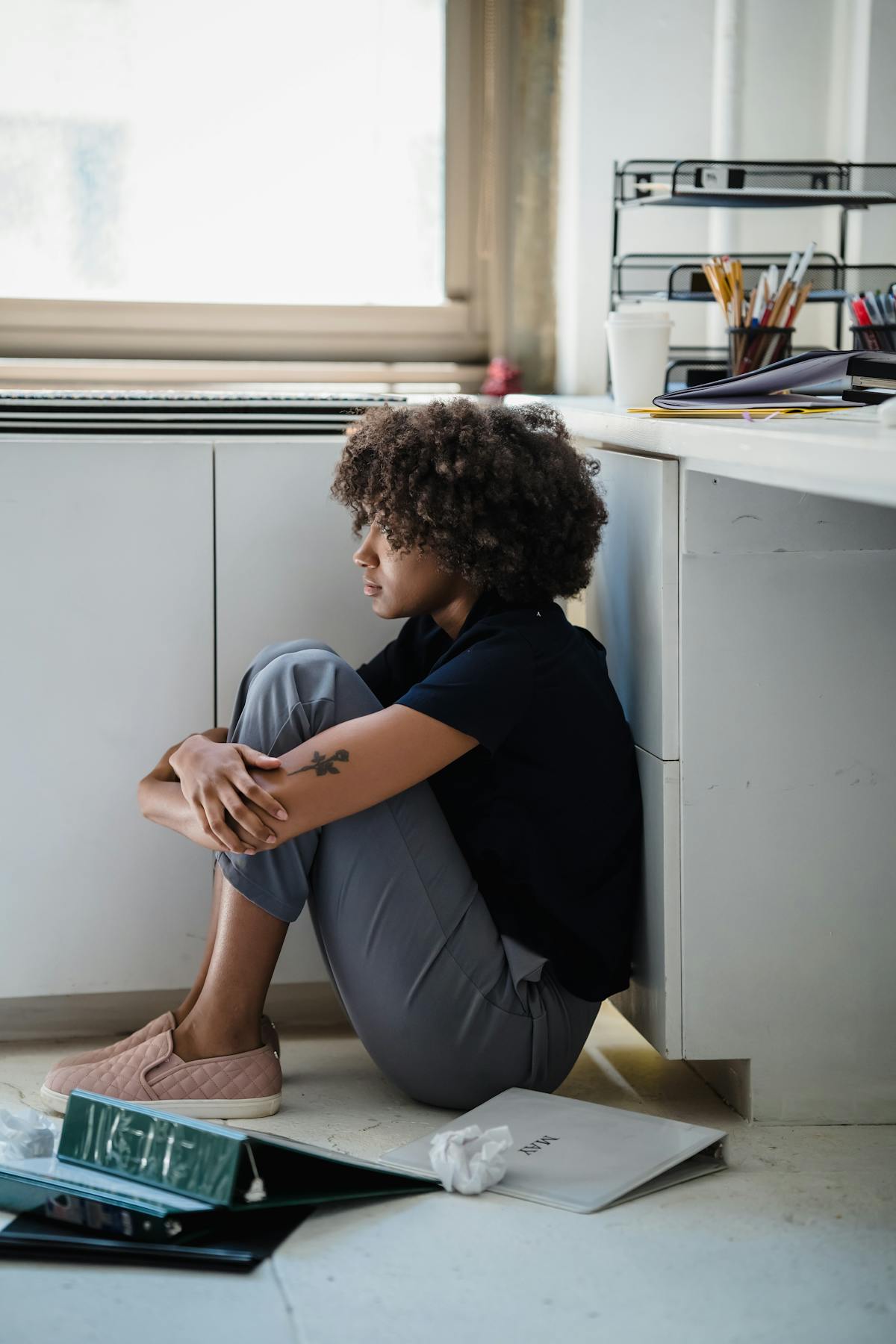 床に座って膝を抱えている疲れた女性