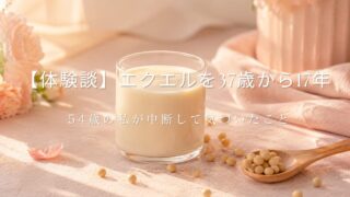やわらかなピンクの背景に、グラスに入った豆乳と木のスプーンにのった大豆、ピンクの花が並ぶ写真。【体験談】エクエルを37歳から17年、54歳の私が中断して気づいたことを綴る記事のアイキャッチ画像。